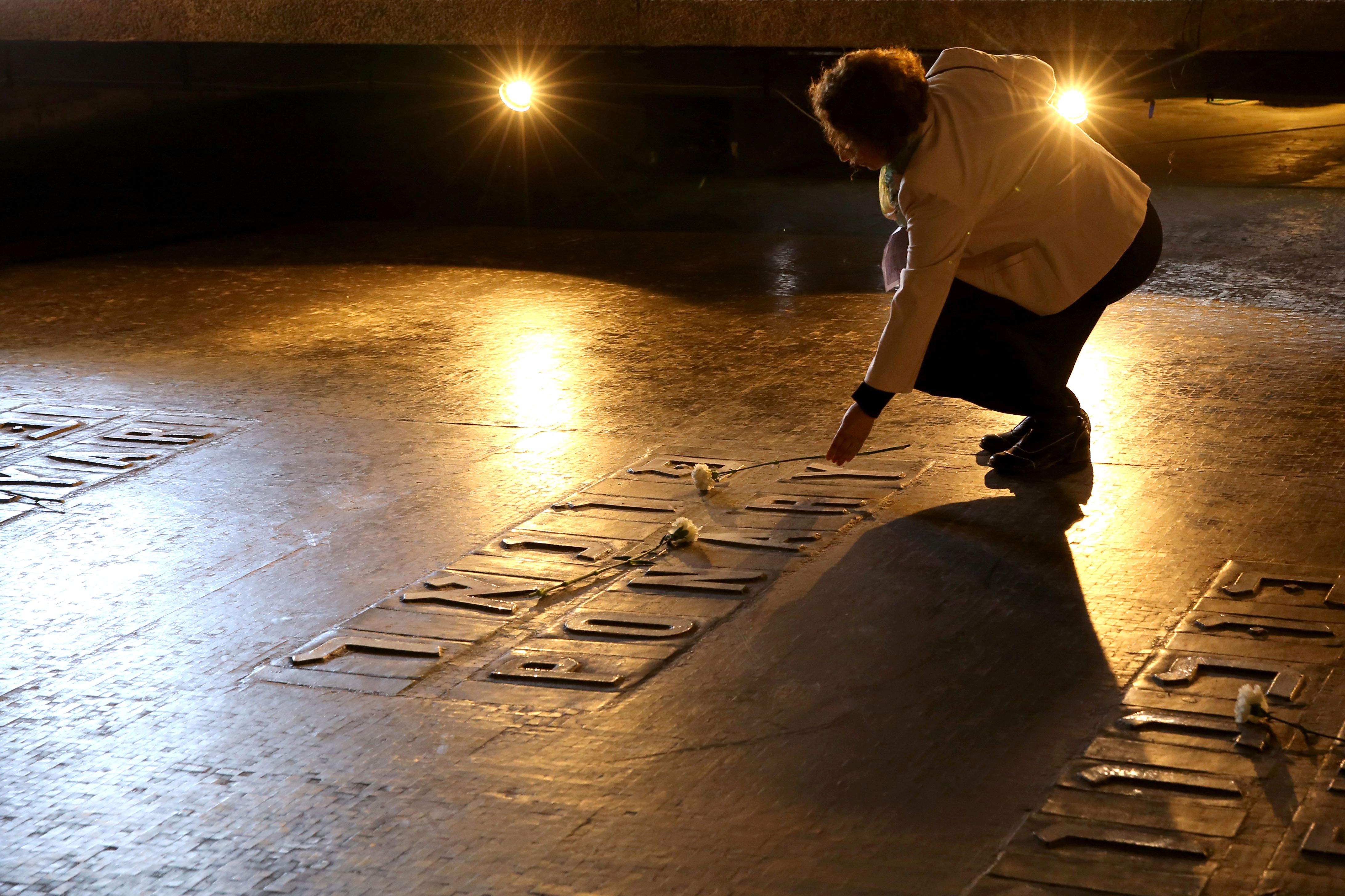 An Israeli relative of Holocaust victims lays a flower at the Hall of Remembrance where the names of major death and concentration camps are written during a ceremony marking the annual Holocaust Remembrance Day at the Yad Vashem Holocaust Memorial in Jerusalem on May 5, 2016. The state of Israel marks the annual Memorial Day commemorating the six million Jews murdered by the Nazis in the Holocaust during World War II. / AFP / GALI TIBBON