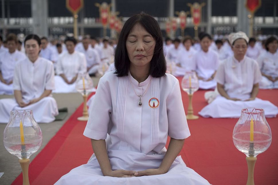 Buddhist devotees meditate during a ceremony in Bangkok on February 22, 2016 on the occasion of Makha Bucha day. The Makha Bucha festival is observed in Thailand on the full moon of the third lunar month and commemorates the day when 1,250 monks gathered to be ordained by the Buddha. AFP PHOTO / Nicolas ASFOURI / AFP / NICOLAS ASFOURI