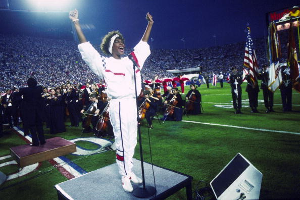 Whitney Houston sings the National Anthem during the pregame show at Super Bowl XXV while tens of thousands of football fans wave tiny American flags in an incredible outburst of patriotism during the Persian Gulf War on 01/27/1991.