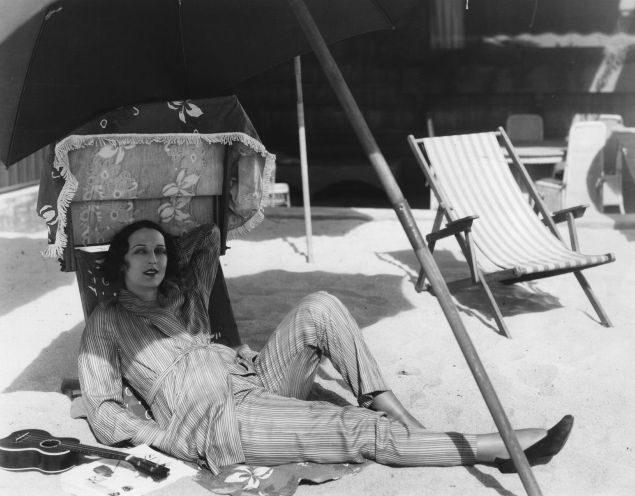 circa 1930:  Vampish American actress Carmel Myers (1899 - 1980), who appeared such MGM films as 'A Certain Young Man', relaxing outdoors with a ukelele and a sunshade.  