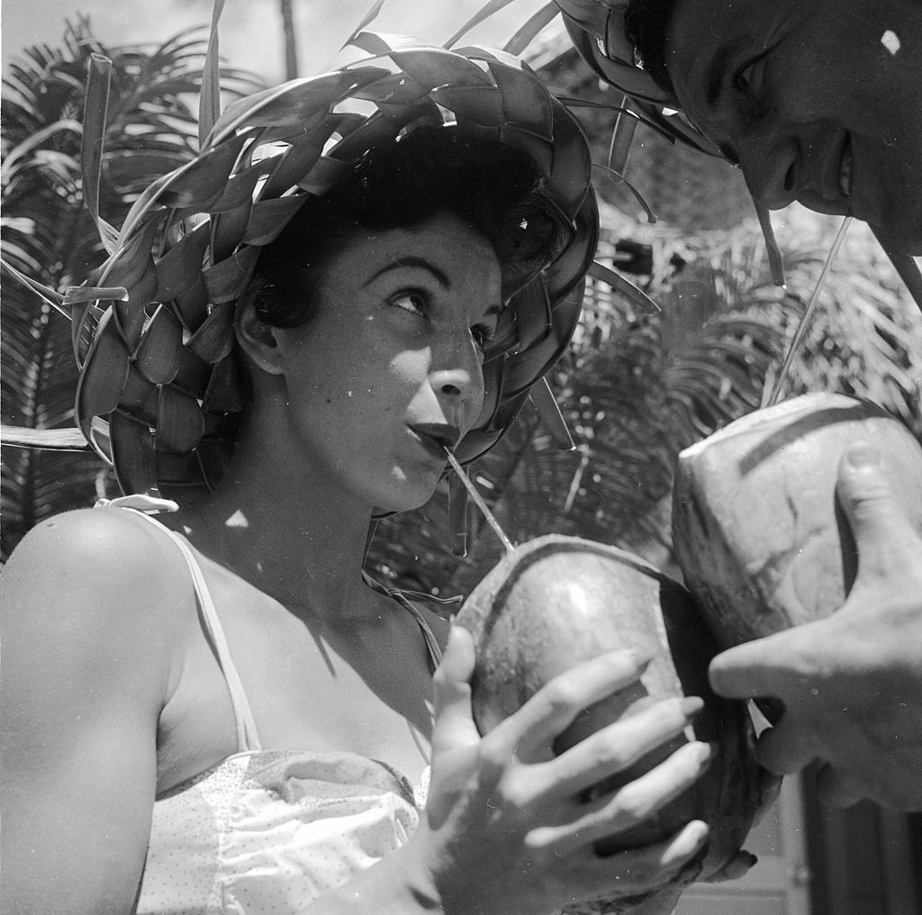 circa 1955: Bert and Ellie Lang, a young American couple on their honeymoon in Hawaii sample a local speciality - coconut cocktail drunk straight out of the shell. 