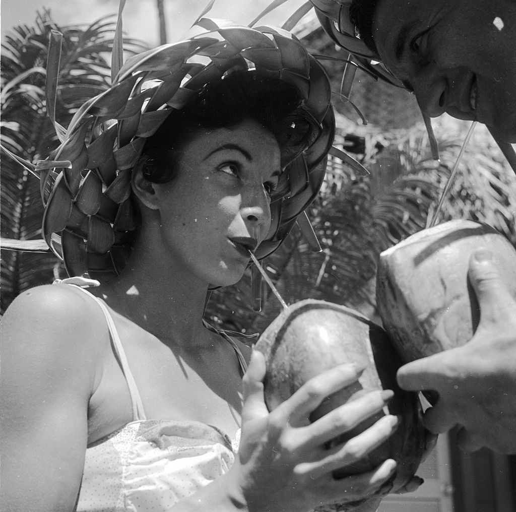 circa 1955: Bert and Ellie Lang, a young American couple on their honeymoon in Hawaii sample a local speciality - coconut cocktail drunk straight out of the shell.