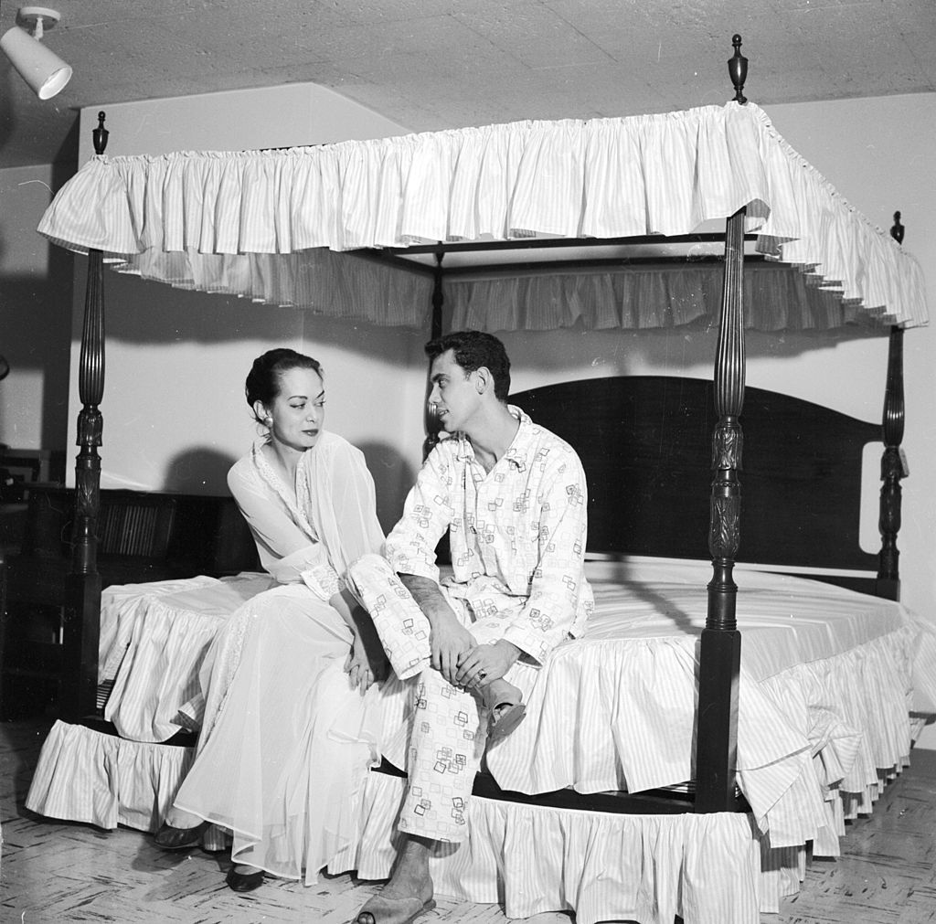 circa 1956: A couple sitting on a specially designed four poster bed. (Photo by Three Lions/Getty Images)