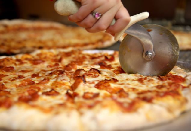 Arlet Lagoa cuts a pizza into slices at Miami's Best Pizza restaurant.