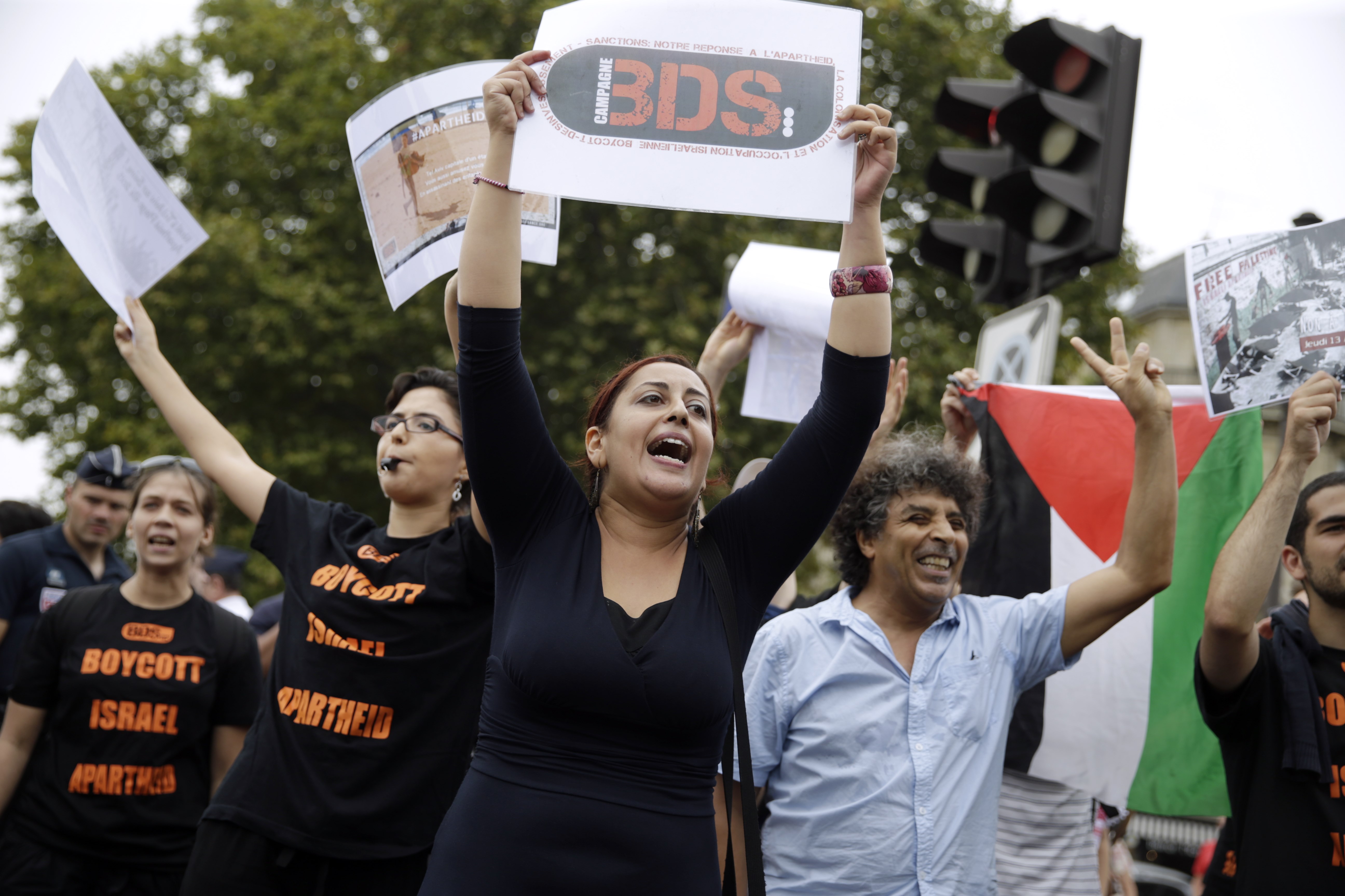 A Pro-Palestinian "Gaza Beach" protestor holds a placard reading "BDS (Boycotts, divestment and sanctions) during a gathering on the sidelines of "Tel Aviv Sur Seine", a beach event celebrating Tel Aviv, in central Paris on August 13, 2015. A Paris beach event celebrating Tel Aviv attracted a handful of visitors but a huge number of journalists, riot police and security guards, as well as a much larger "Gaza Beach" protest. Bemused locals who headed down to "Tel Aviv Sur Seine" had to manoeuvre through bag checks, security pat-downs and metal detectors to reach the small stretch of sand on the banks of the Seine. AFP PHOTO / KENZO TRIBOUILLARD
