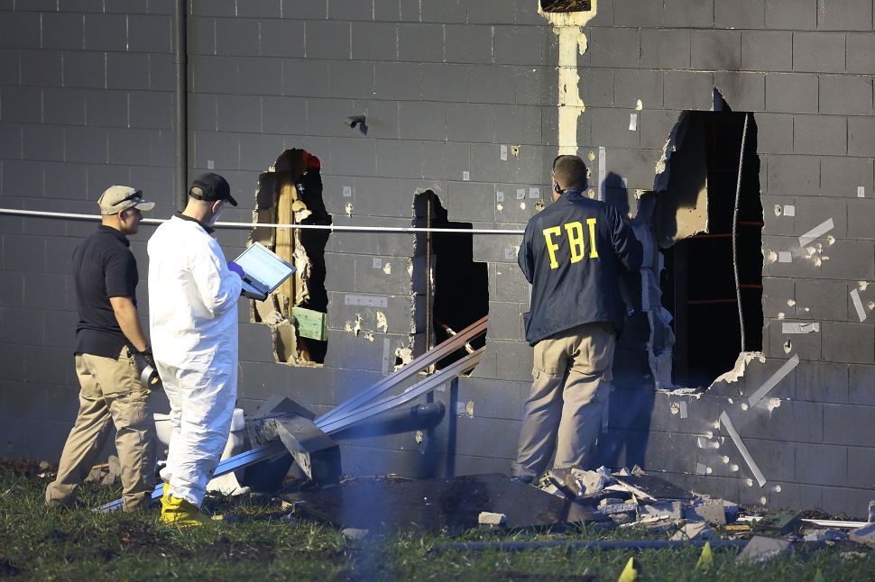 FBI agents investigate near the damaged rear wall of the Pulse Nightclub where Omar Mateen allegedly killed dozens on June 12, 2016 in Orlando, Florida.