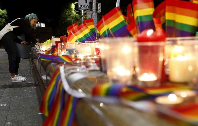 A woman lights a candle during a candlelight vigil for the victims of the Pulse Nightclub shooting in Orlando, Florida, at Oxford St on June 13, 2016 in Sydney, Australia.