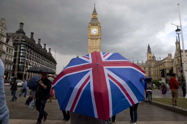 A pedestrian shelters from the rain beneath a Union flag themed umbrella as they walk near the Big Ben clock face and the Elizabeth Tower at the Houses of Parliament in central London on June 25, 2016, following the pro-Brexit result of the UK's EU referendum vote. 