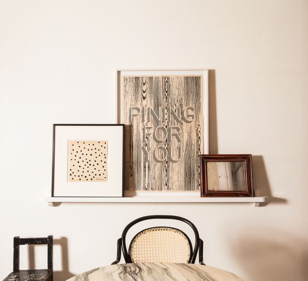 A framed art collection sits above the marble dining table