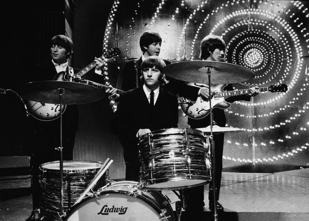 The Beatles perform live on stage in front of a circular lit backdrop at the BBC TV Centre, June 1966.
