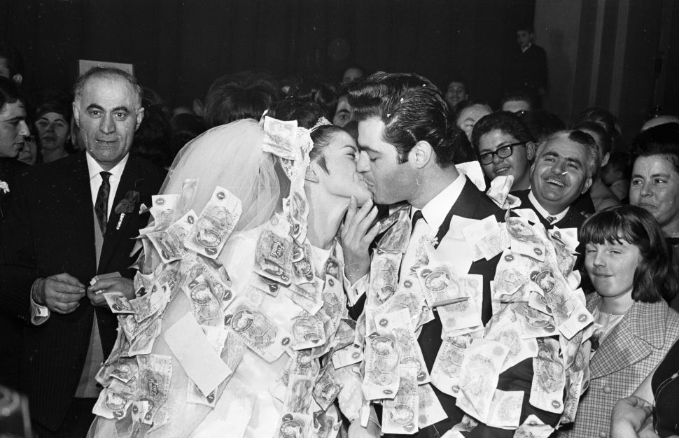 23rd November 1965: Daniel Americanos and his bride at their reception at Stoke Newington town hall, London. According to Greek tradition guests pin money on to the clothes of the happy couple.