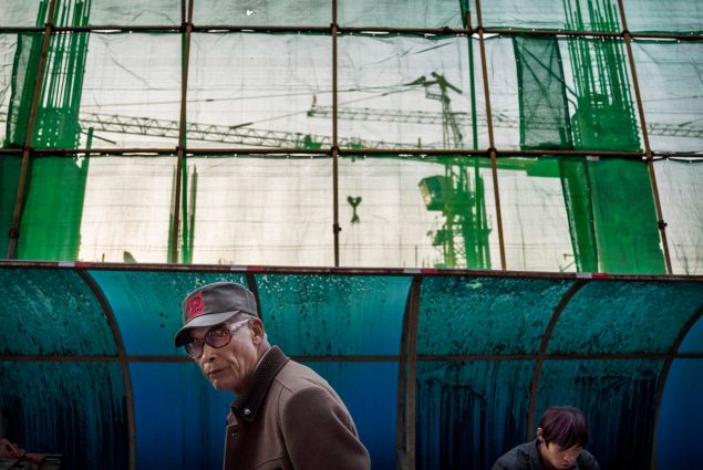 BEIJING, CHINA - OCTOBER 27: A Chinese man walks past a major construction project in a Hutong, or traditional neighborhood on October 27, 2014 in Beijing, China. Economic data show that the country's growth dropped to a five year low and is slowing due to a decrease in exports and property development in recent months, reports say.