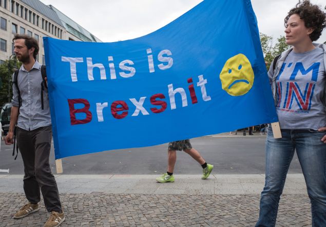 Demonstrators hold a banner reading "This is Brexshit" during a protest near Britain's embassy in Berlin on July 2, 2016. Some 20 demonstrators, mostly British expats living in Berlin, protested against the outcome of the recent "Brexit" referendum, expressing their allegiance to the EU. / AFP / John MACDOUGALL 