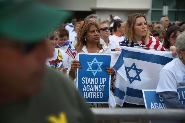 Sonja Blencowe (L) and Jordan Weil stand together during a moment of silence for the French people during a community rally for "Never Again" on November 15, 2015 in Miami Beach, Florida. 