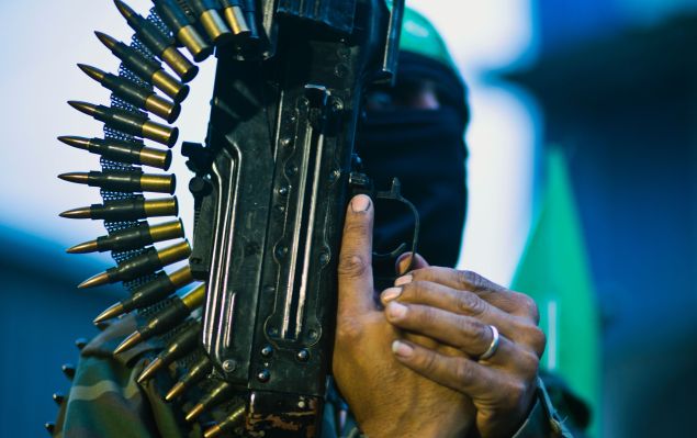 A member of the Ezzedine al-Qassam Brigades, the military wing of the Palestinian Islamist movement Hamas holds his weapon during a rally to mark the 12th anniversary of the death of assassinated Hamas spiritual leader Sheikh Ahmed Yassine on March 23, 2016 outside his home in Gaza city. / AFP / MAHMUD HAMS