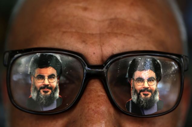 A souvenir shop owner displays glasses decorated with pictures of Hassan Nasrallah, the head of Lebanon's powerful Shiite militant group Hezbollah, in Beirut southern suburb on May 12, 2016.
