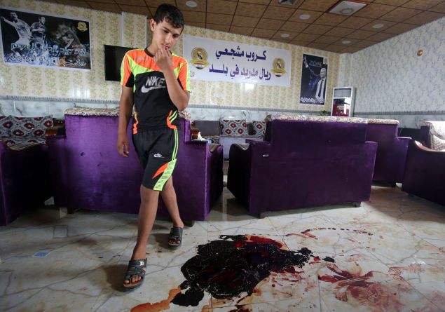 TOPSHOT - An Iraqi boy walks past the blood stains and debris at a cafe, that was popular with local fans of Spain's Real Madrid football club, in the Balad area, north of the capital Baghdad, on May 14, 2016, a day after a deadly raid claimed by Islamic State group militants. At least 16 people were killed and 30 wounded, including several members of the security forces, in the attack in the town of Balad and the ensuing chase, officials said. / AFP / AHMAD AL-RUBAYE 