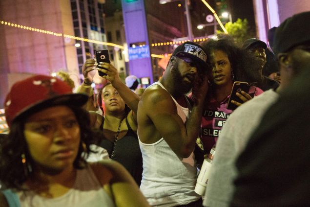 Protestors yell after police officers arrest a bystander following the shooting at a protest in Dallas on July 7, 2016. A fourth police officer was killed and two suspected snipers were in custody after a protest late Thursday against police brutality in Dallas, authorities said. One suspect had turned himself in and another who was in a shootout with SWAT officers was also in custody, the Dallas Police Department tweeted. / AFP / Laura Buckman