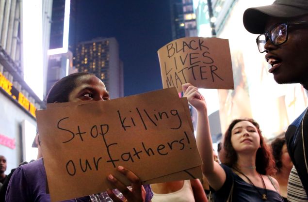Activists hold signs in Times Square as they protest the recent fatal shootings of two black men by police.