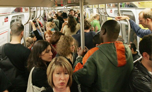 Subway passengers ride a crowded L train.