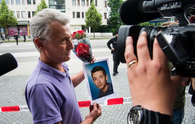 MUNICH, GERMANY - JULY 23: The father of one of the victims is showing flowers and a picture of his son (on the picture his son is named as Zabergja Dijamant) as he arrives outside the OEZ shopping center the day after a shooting spree left nine victims dead on July 23, 2016 in Munich, Germany. According to police an 18-year-old German man of Iranian descent shot nine people dead and wounded at least 16 before he shot himself in a nearby park. For hours during the spree and the following manhunt the city lay paralyzed as police ordered people to stay off the streets. Original reports of up to three attackers seem to have been unfounded. The shooter's motive is so far unclear.