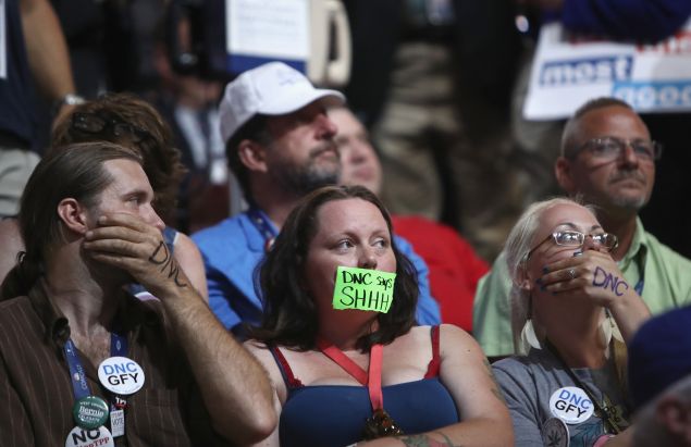 Sanders supporters cover their mouths during roll call on the second day of the Democratic National Convention at the Wells Fargo Center, July 26, 2016 in Philadelphia.
