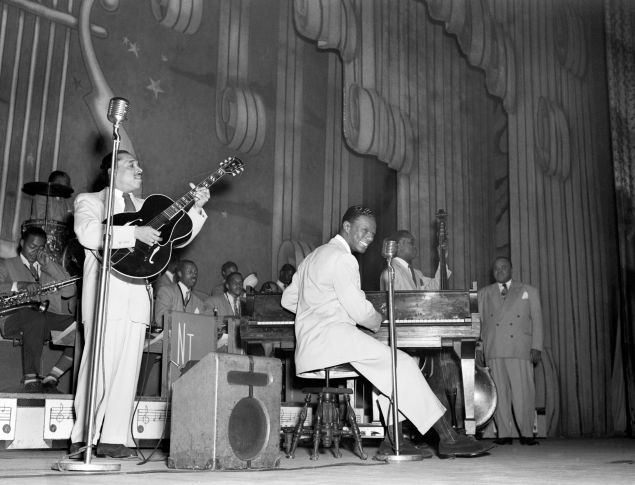 Nat King Cole plays with his jazz orchestra on the stage of the Apollo Theatre, in Harlem, in New York in the 1950s.