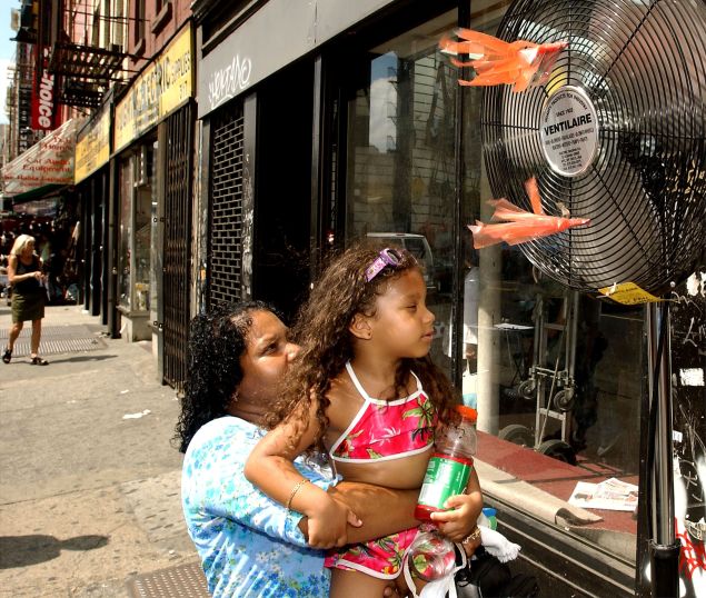 A woman holds her daughter up to a fan to cool off during a 2002 heat wave in New York City.