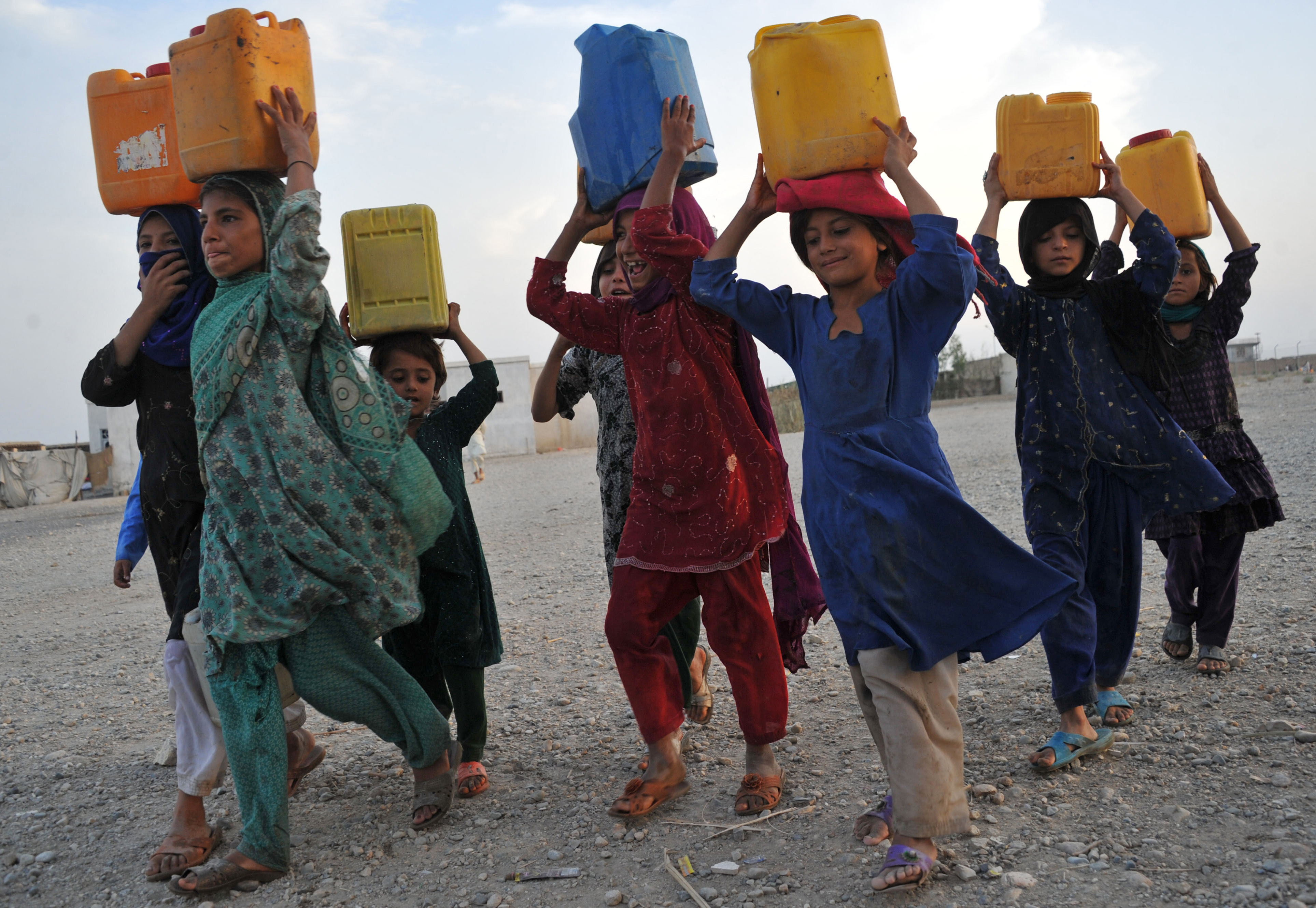 Internally displaced Afghan refugee children transporting water.