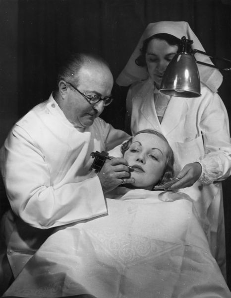 1937: Plastic surgeon J C Bell at work on a customer's face in his beauty parlour. (Photo by Fox Photos/Getty Images)