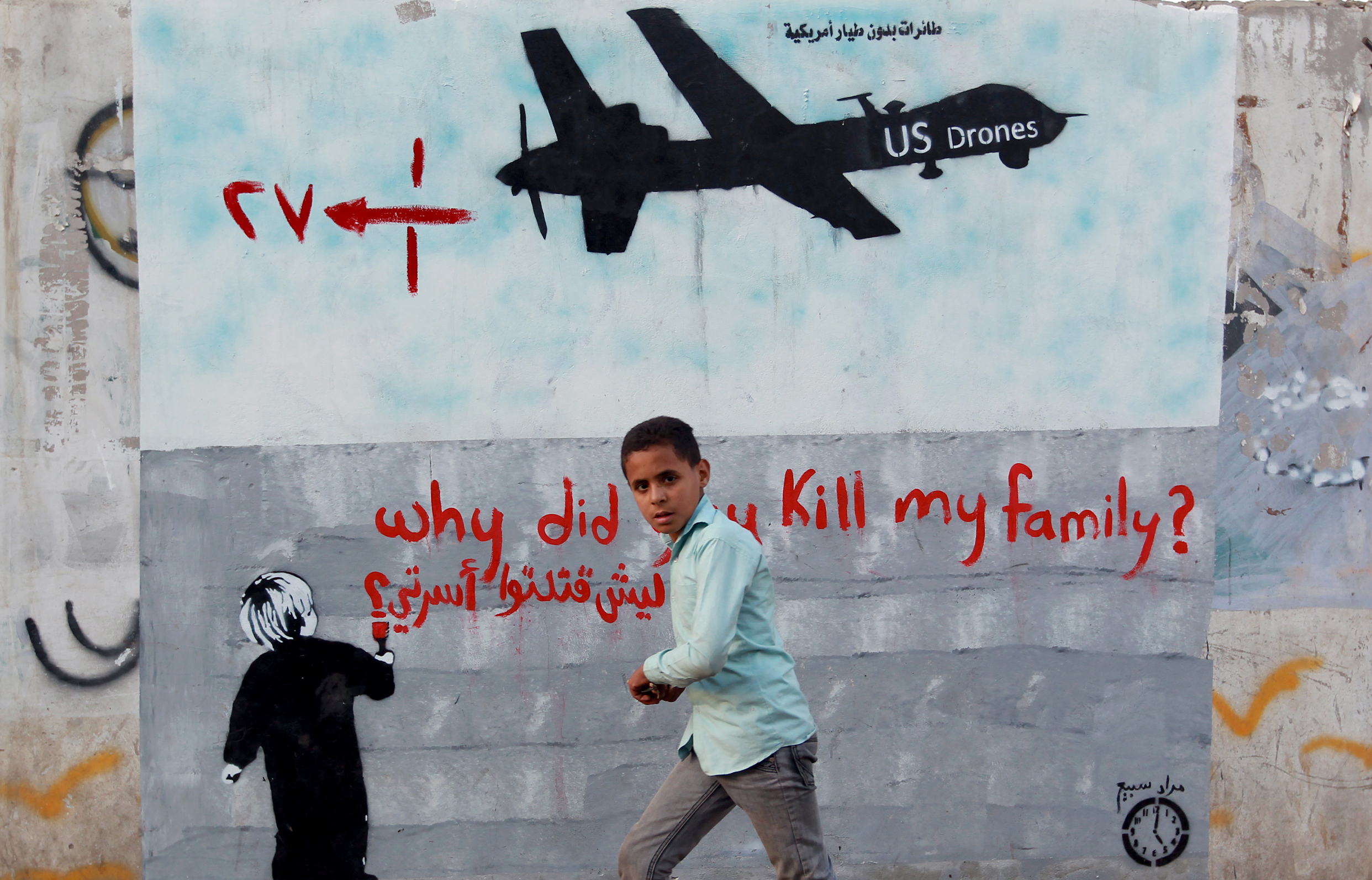 A boy walks past graffiti denouncing strikes by U.S. drones in Yemen, painted on a wall in Sanaa, Yemen.