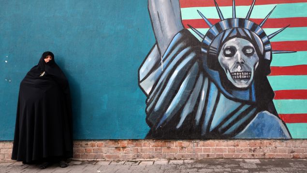 An Iranian woman stands in front of the painted wall of the former US embassy on November 4, 2014 in Tehran where takes place a demonstration to mark the anniversary of its storming by student protesters that triggered a hostage crisis. Thousands of Iranians shouted "Death to America" during the demonstration, 35 years after Islamist students stormed the embassy compound, holding 52 American diplomats hostage for 444 days. The painting shows the Statue of Liberty with a skull as a face.
