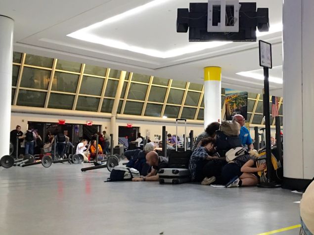 Passengers get down at the immigration control while police looking for an active shooter at JFK International airport in New York on August 14, 2016.