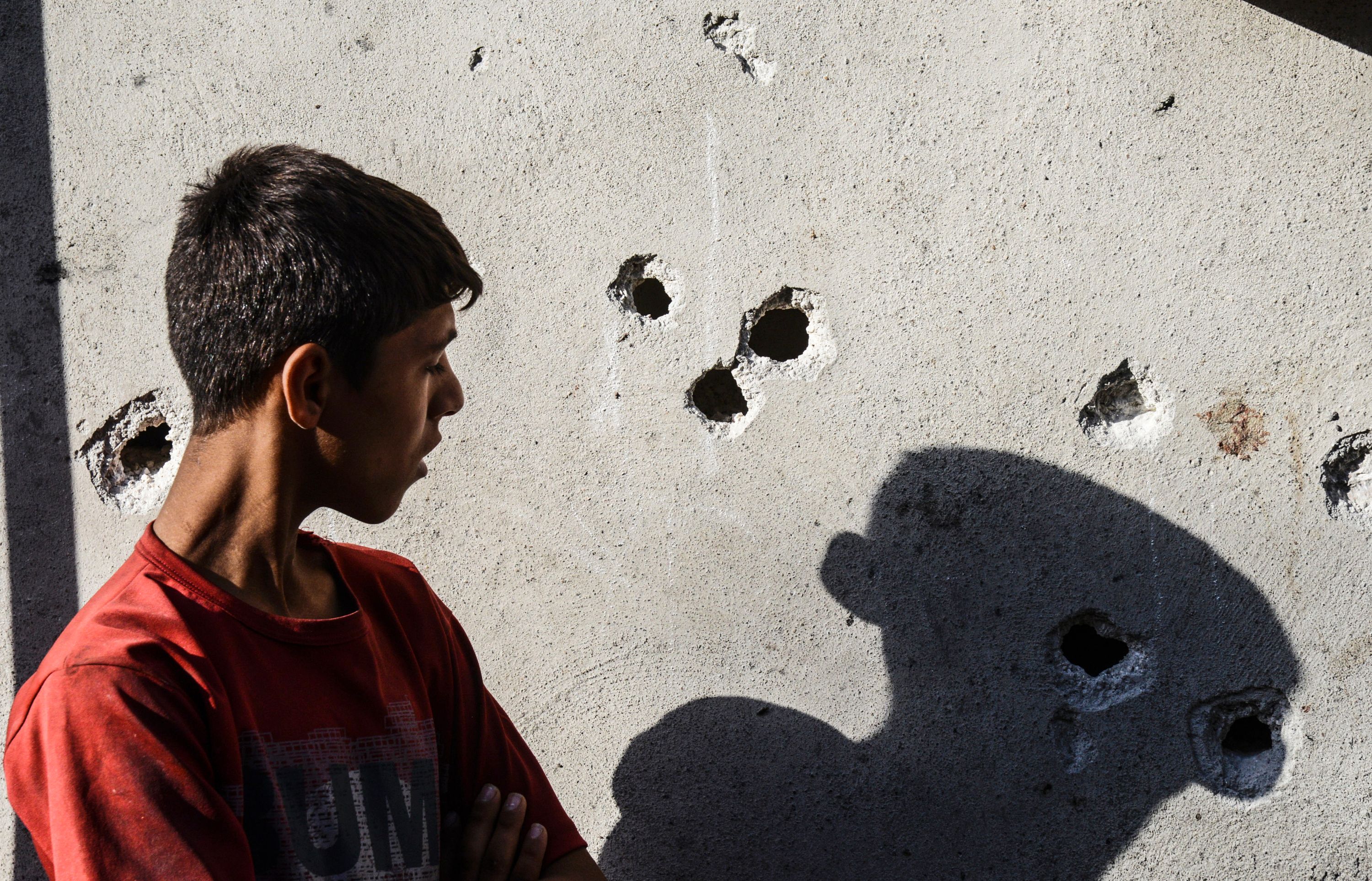 A boy stands near impacts of projectile on a wall near the explosion scene in Gaziantep in southeastern Turkey near the Syrian border on August 21, 2016. Turkish President Recep Tayyip Erdogan on Sunday said the Islamic State (IS) group was the "likely perpetrator" of the bomb attack.