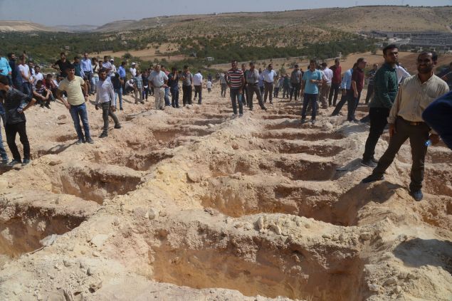 People wait close to empty graves at a cemetery during the funeral for the victims of last night's attack on a wedding party that left 50 dead in Gaziantep in southeastern Turkey near the Syrian border on August 21, 2016. At least 50 people were killed when a suspected suicide bomber linked to Islamic State jihadists attacked a wedding thronged with guests, officials said on August 21. Turkish President Recep Tayyip Erdogan said the IS extremist group was the "likely perpetrator" of the bomb attack, the deadliest in 2016, in Gaziantep late Saturday that targeted a celebration attended by many Kurds. 