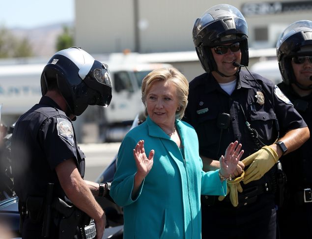 RENO, NV - AUGUST 25: Democratic presidential nominee former Secretary of State Hillary Clinton talks with Reno police officers before getting onto her plane at Reno Tahoe International Airport on August 25, 2016 in Reno, Nevada. Hillary Clinton delivered a speech about republican presidential nominee Donald Trump's policies