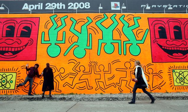 NEW YORK - MAY 02: People walk by a re-creation of an untitled mural painted by artist Keith Haring on the corner of Houston Street and Bowery in Manhattan May 2, 2008 in New York City. Marking the 50th anniversary of Haring's birth on May 4, a team of artists recreated the mural which was originally done in 1982 as Haring's first major outdoor project. The original mural only existed for a few months before the Day-Glo colors began to decompose in the sun and Haring painted over the piece. 