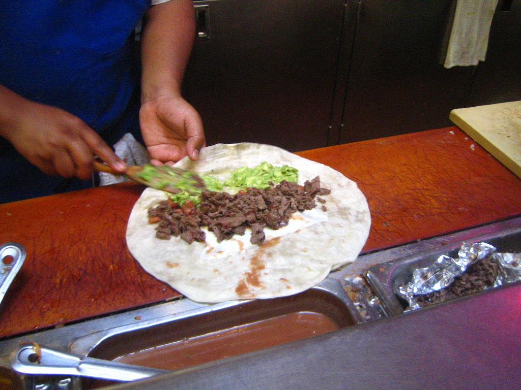 Somebody making a burrito at a burrito joint in the Mission. 