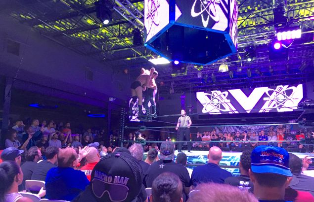 Dustin prepares to superplex Drew Gulak off the top rope.