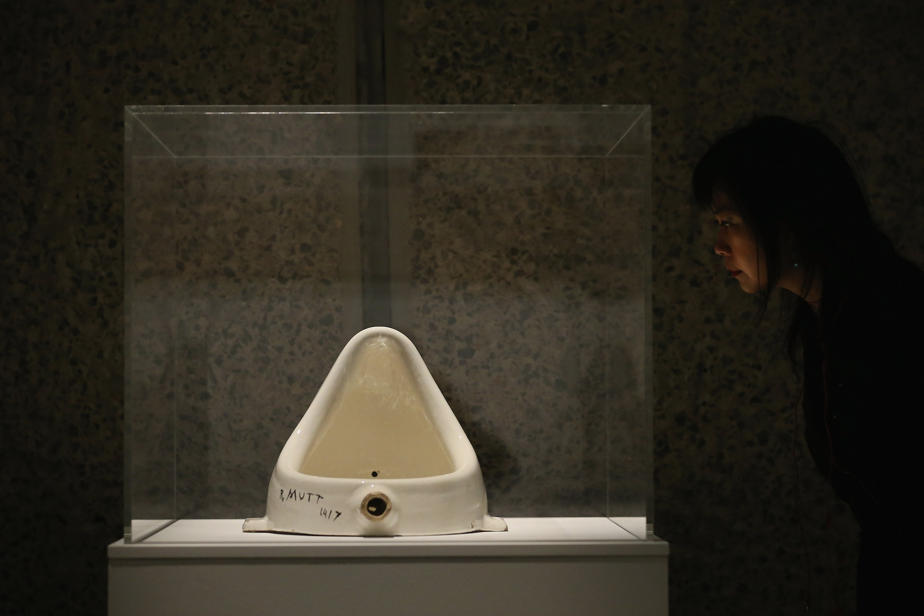 A woman looks at a piece of work entitled 'Fountain' by Marcel Duchamp during a press preview of 'The Bride and the Bachelors' exhibition at the Barbican Art Gallery on February 13, 2013 in London, England. The piece makes up a selection of works by artists and choreographers including Marcel Duchamp, Merce Cunningham, John Cage, Robert Rauschenberg and Jasper Johns, and runs at the Barbican Art Gallery until June 9, 2013.