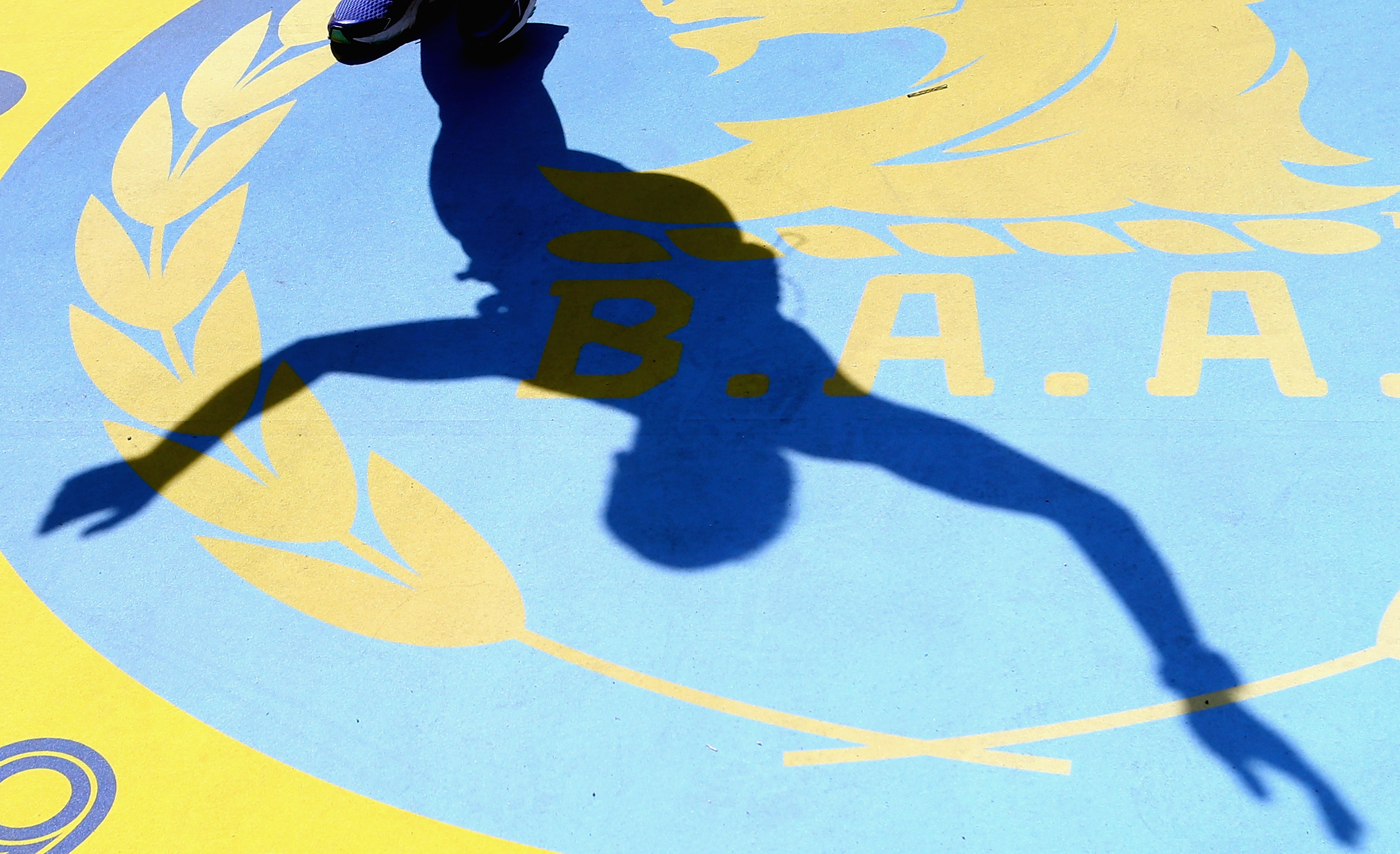 A runner's shadow is seen crossing the finish line during the 120th Boston Marathon.