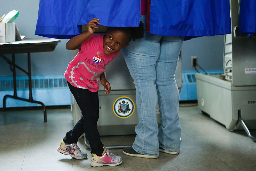 A young girl looks out of a voting booth during Pennsylvania's primary election on April 26, 2016 in Philadelphia, Pennsylvania.