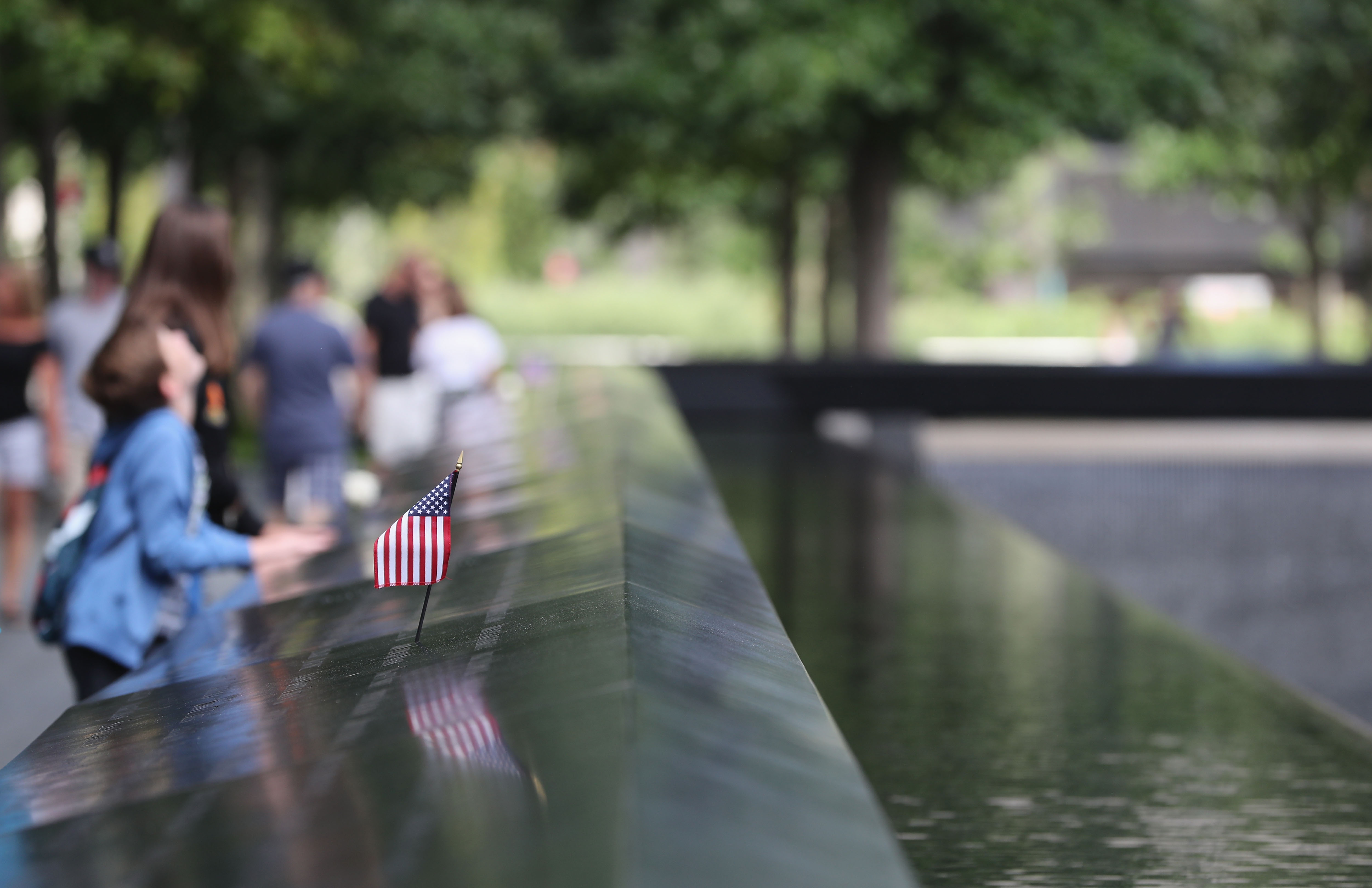 A young boy looks up to One World Trade Center next to a US flag at the the 9/11 memorial site.