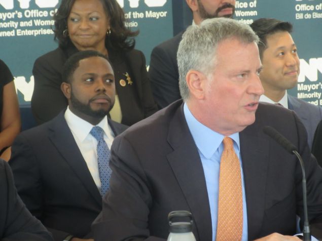 Mayor Bill de Blasio announces a new vision for the city's MWBE program, with his senior MWBE adviser, Rev. Jonnel Doris, behind him.