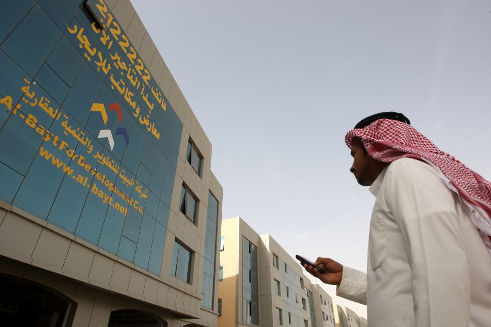 TO GO WITH AFP STORY BY PAUL HANDLEYA Saudi man takes the number of a real estate company from the facade of a building on King Fahd road in the Saudi capital Riyadh on December 14, 2010 where one office building after another sports a gigantic telephone number: the international sign of a desperate search for tenants. AFP PHOTO/HAMAD OLAYAN 