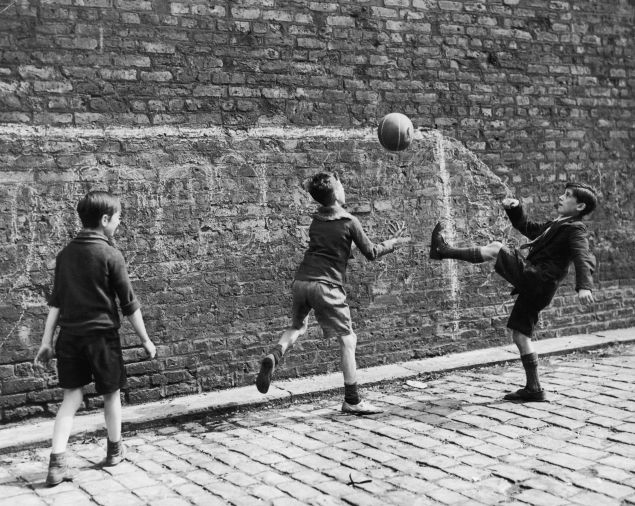 A group of boys playing soccer in the street in Salford, Lancashire.