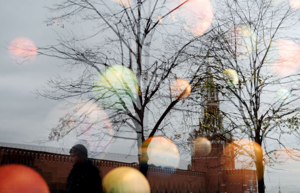 A man is reflected on a shop window as he walks along Red Square, with the Kremlin's Spasskaya (Saviour) Tower seen in the background, in central Moscow on October 11, 2016. / AFP / Natalia KOLESNIKOVA