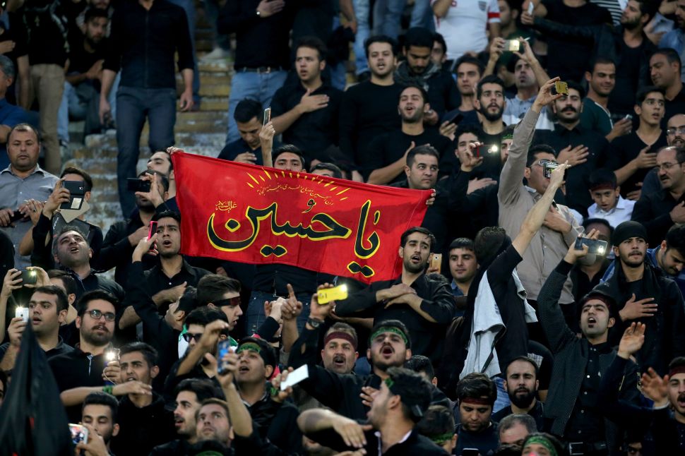 Iranian fans wave a religious banner to mark Ashura, which marks the death of Prophet Mohammed's grandson Imam Hussein in the seventh century, during the 2018 World Cup qualifying football match between Iran and South Korea at the Azadi Stadium in Tehran on October 11, 2016. / AFP / ATTA KENARE