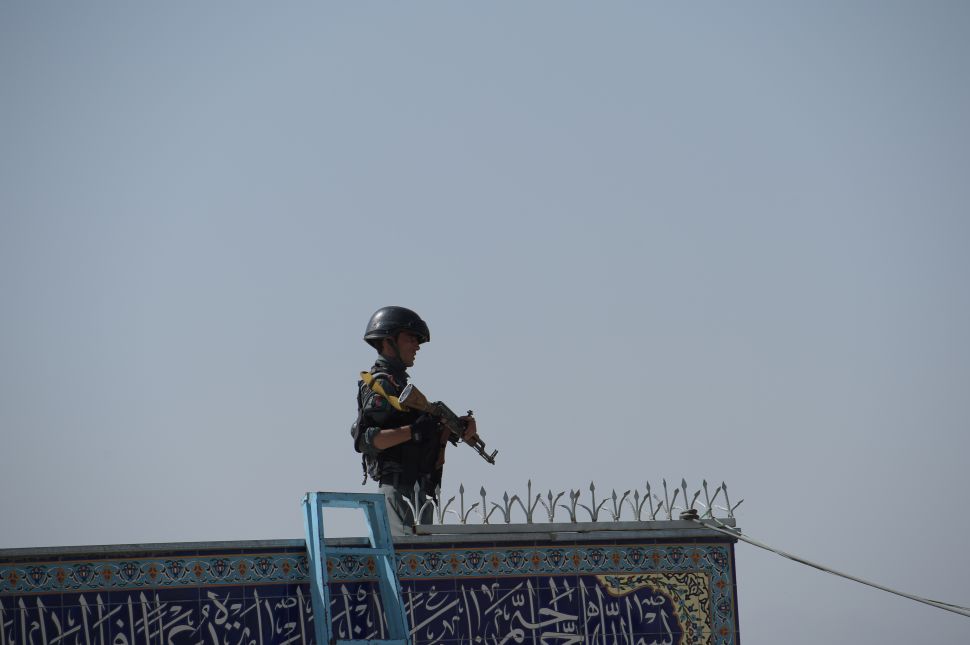 An Afghan policeman keeps watch inside the Karte Sakhi shrine in Kabul on October 12, 2016, after an attack by gunmen late on October 11. Grieving worshippers on October 12 described desperately trying to shelter their children against a hail of gunfire in Kabul that killed at least 18 people gathering to mark Ashura, one of the most important festivals of the Shiite calendar. / AFP / SHAH MARAI
