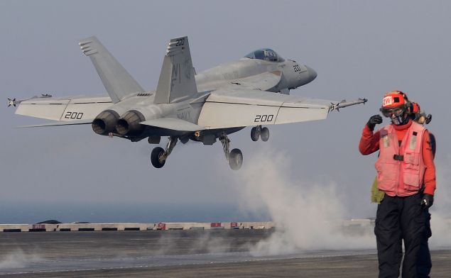 U.S. Navy crew members guide an F/A-18 Super Hornet fighter takes off from the deck of USS Aircraft Carrier Ronald Reagan on October 14, 2016.